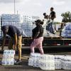People lifting pallets of water.