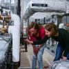 Two students checking the temperature and pressure settings for a rooftop HVAC unit in the Larson Laboratory.