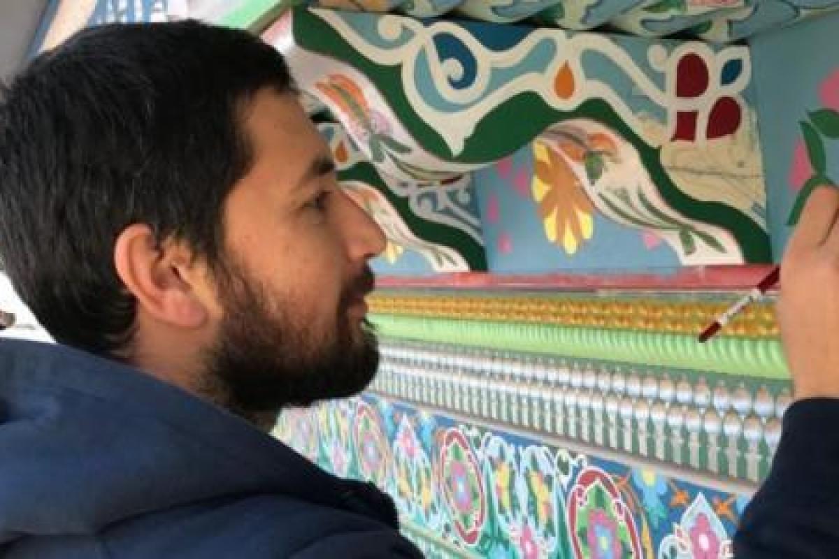 Maruf painting and restoring the trim of the Boulder Dushanbe Teahouse