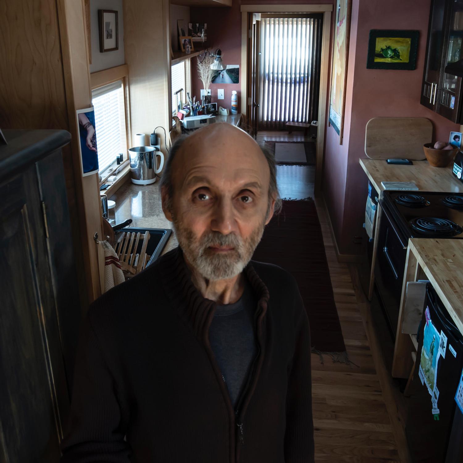 Tom Sundro Lewis stands in his kitchen