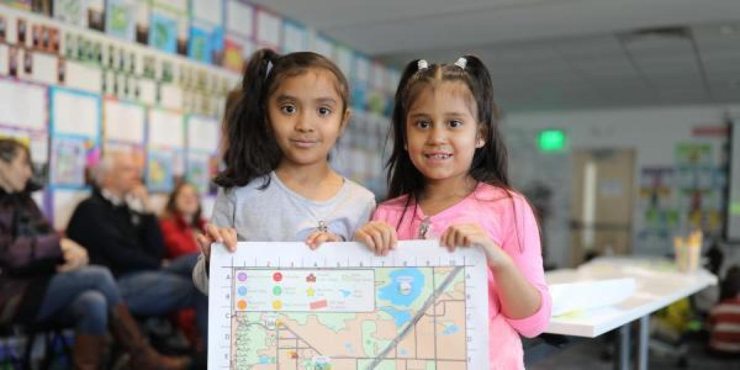 Two children hold up Boulder's first child-friendly map