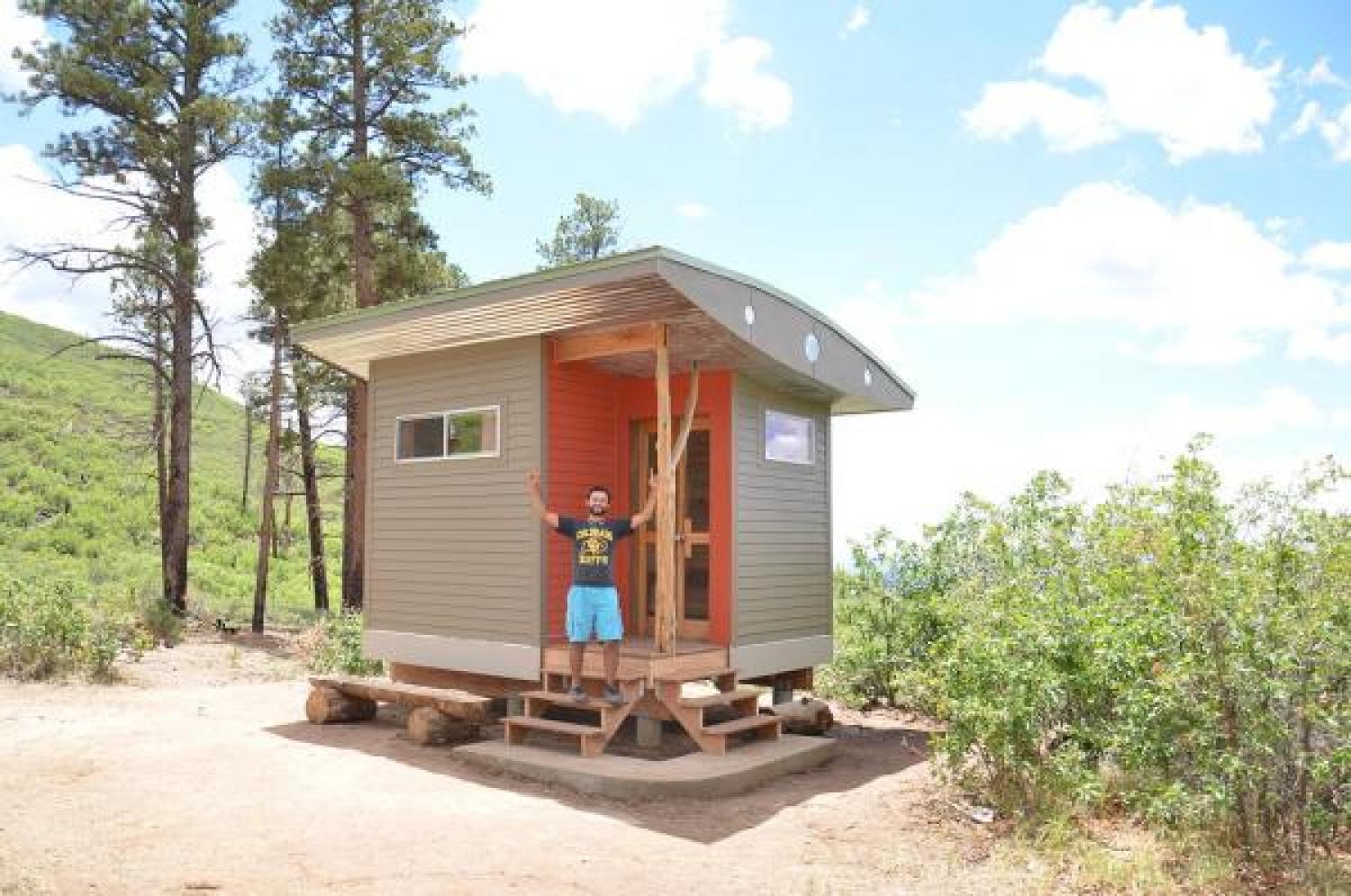 Student in front of tiny house Lama project in New Mexico, built by students.