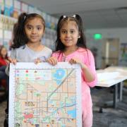 Two young students hold a draft of the child-friendly map