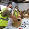 People with masks on organizing food at a food bank.