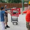 Three children hold red frames around an abandoned cart in a playground, signifying they don't like to see carts in their playgrounds.