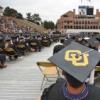 A graduation ceremony from the back with CU on a student's cap in the foreground.