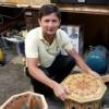 Marufjon (Maruf) Mirakhmatov squats next to a small table from the Boulder Dushanbe Teahouse.