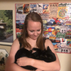 Sarah Kitchen holding a black cat and looking down at it.