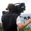 A cameraman trains his equipment on a landscape in a natural setting.