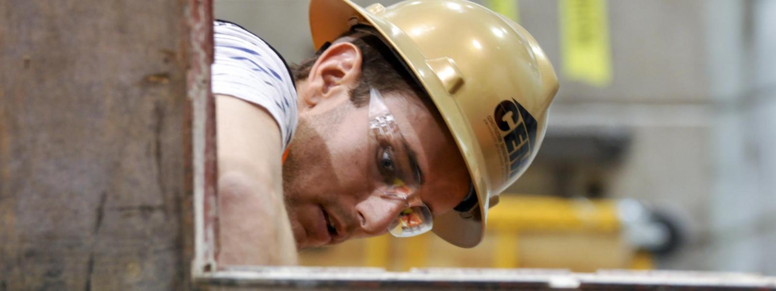 A student works on a steel frame in a lab.