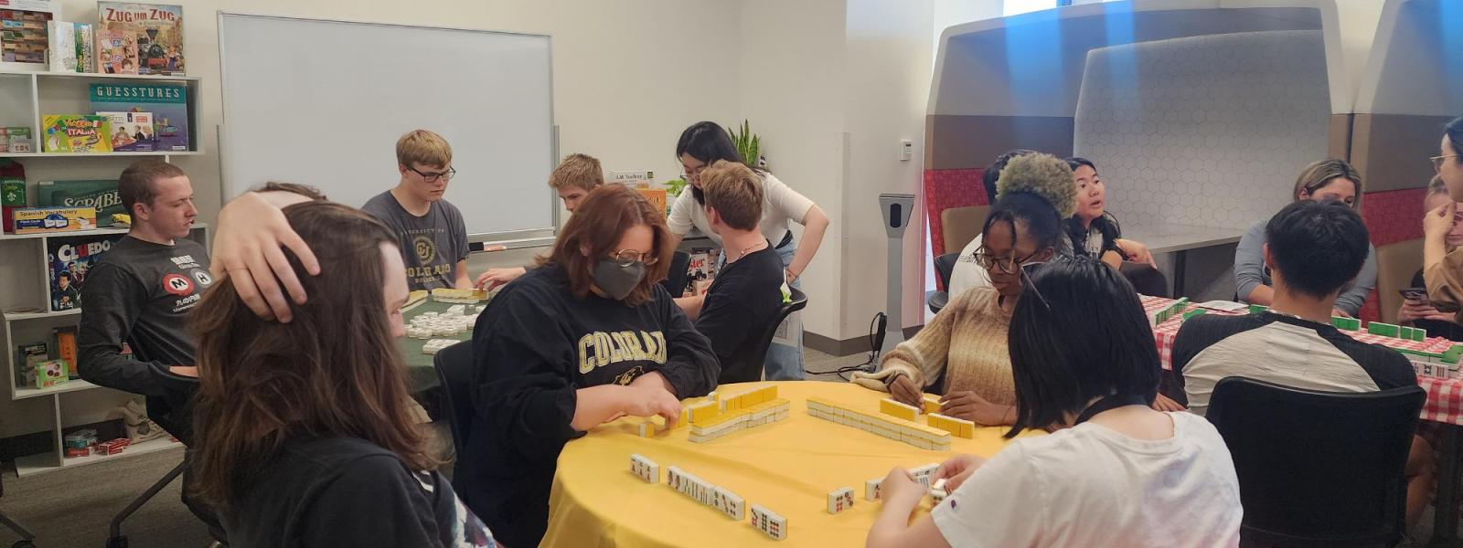 Students gathered around tables playing Mahjong