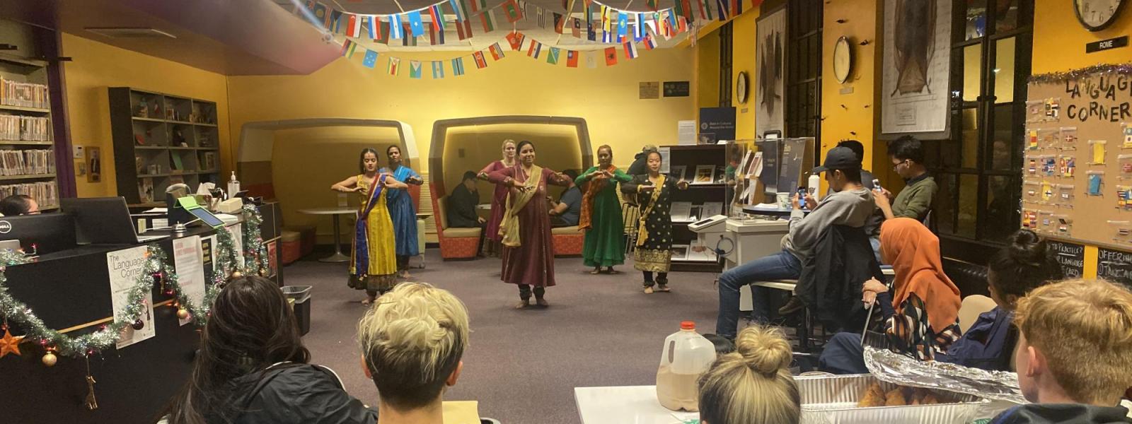 Women dancing a traditional Indian dance in front of an audience in brightly colored dresses
