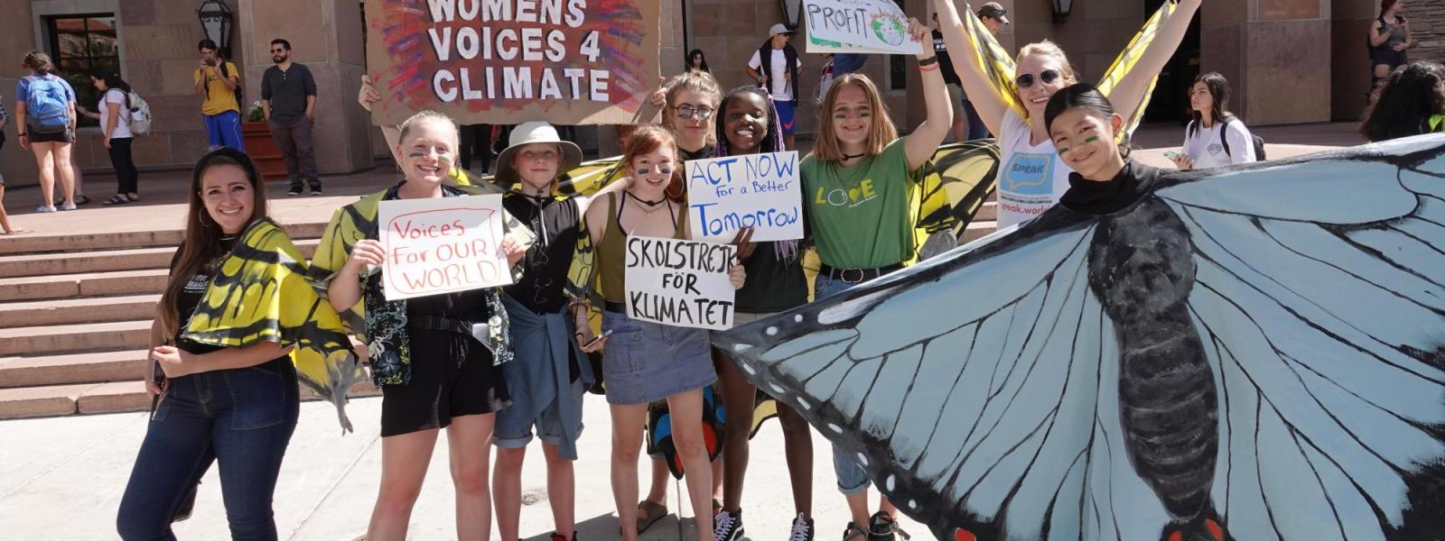 high school women dressed as a butterfly and holding signs for climate action