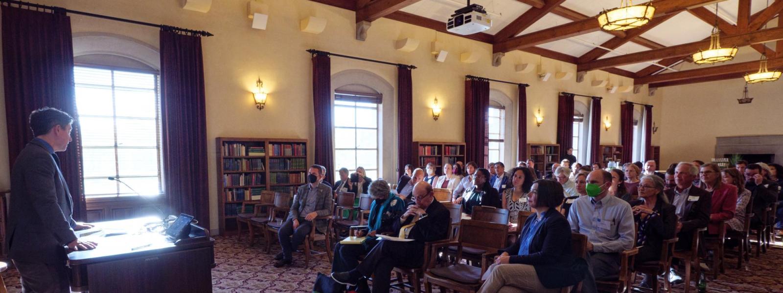 Man speaking at a podium in front of a room of adults seated