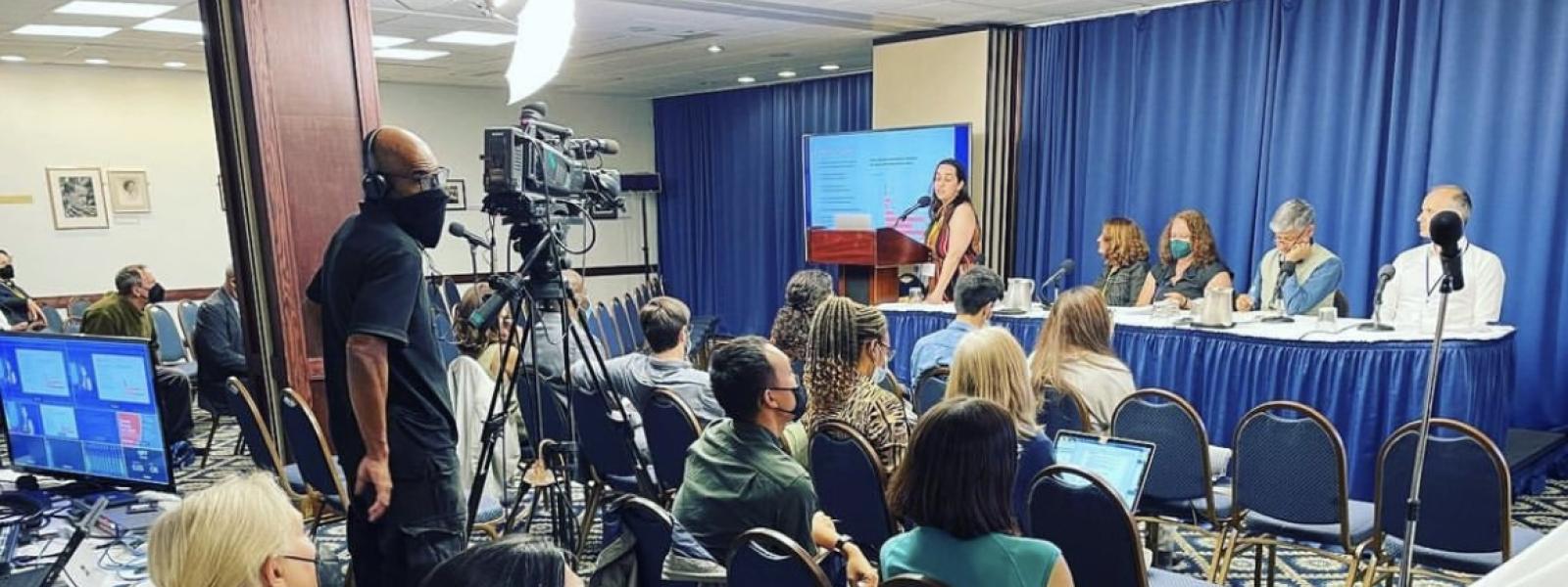 Panel in the National Press Room of DC, addressing seated peopel and cameras