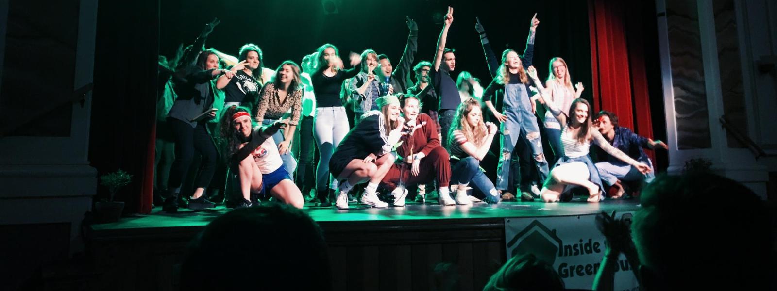 Students on stage posing and smiling, end of Climate Comedy event
