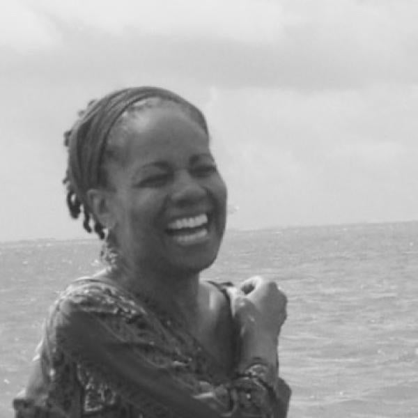 Michele D Simpson black and white photograph smiling standing in front of ocean water.