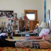 Man on bed with filmmaker Lynne Sachs visible in a mirror in the background. Still from Sachs's doucmentary Film About a Father Who (2020).