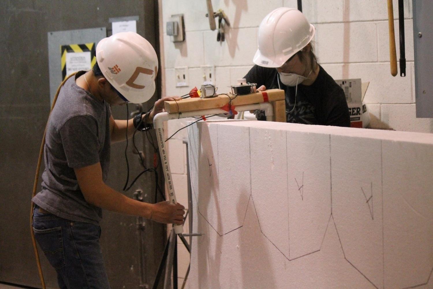 Two students cut Styrofoam to make the mold for the concrete canoe.