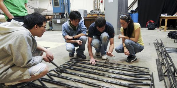 A group of students discuss the design of their steel bridge. 