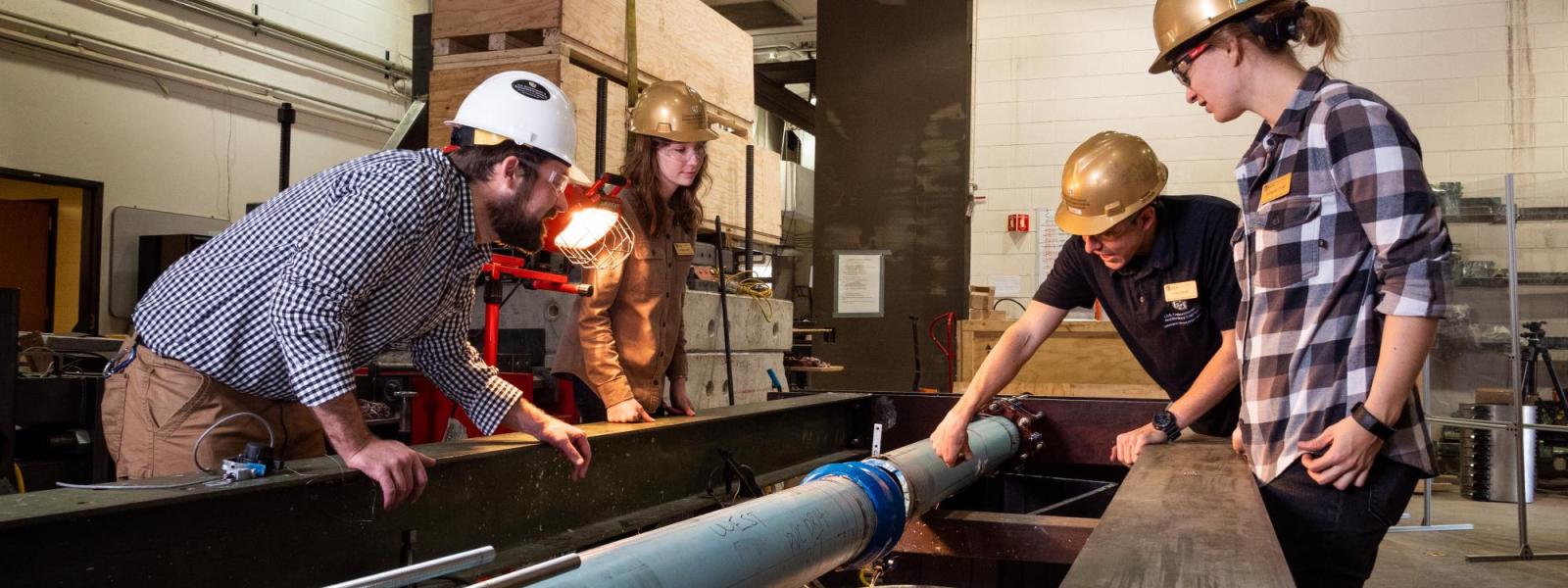 CIEST team members examine the joint of a PVC pipe in an axial load frame