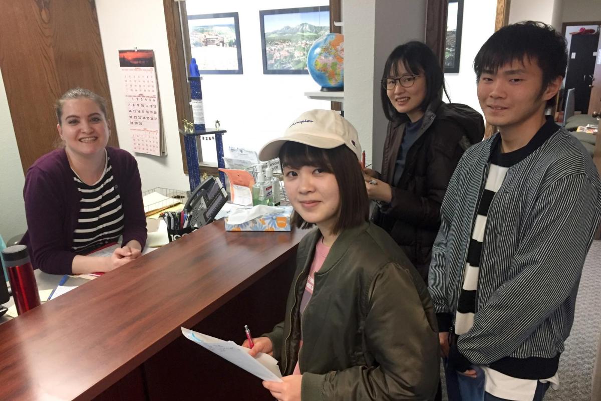 Students stand at the front desk in the front office.
