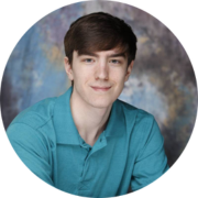 Man with brown hair smiling and wearing a teal short sleeved shirt