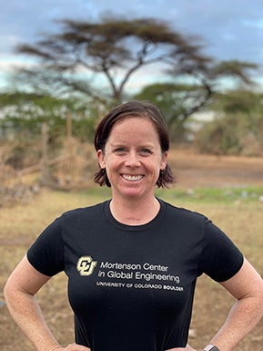 Staff member smiling standing in a T-shirt in an African landscape