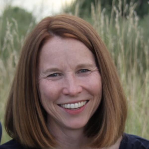 Woman with short red hair stands in grass
