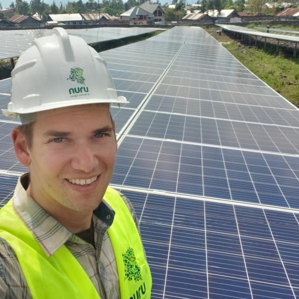 Student smiling standing in front of solar panels