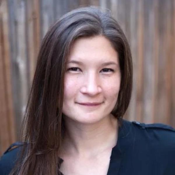 Woman with long brown hair smiling wearing a black shirt