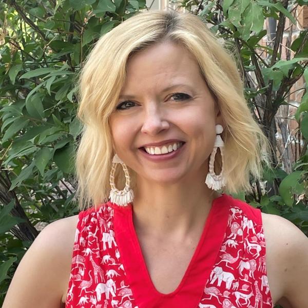 woman standing in front of bush with red shirt and white earings