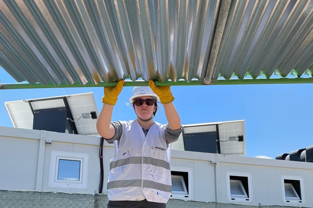 woman in hardhat holding up sheet metal