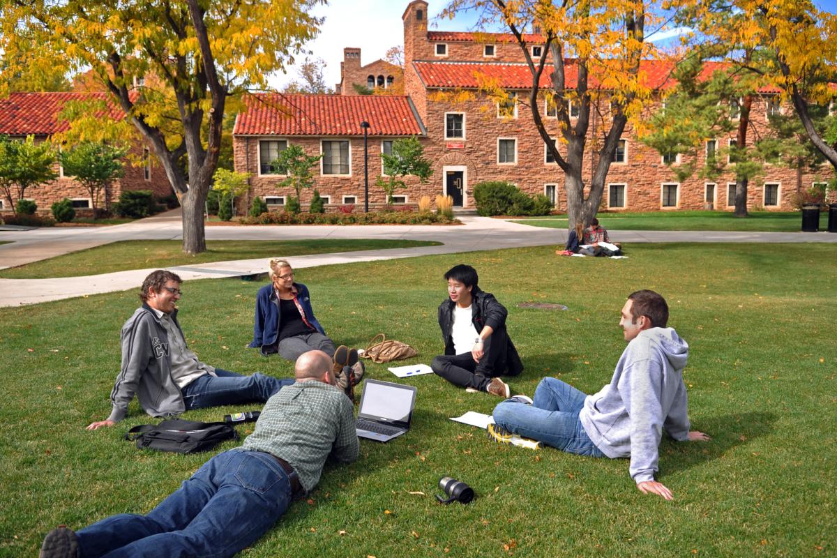students sitting on lawn in fall