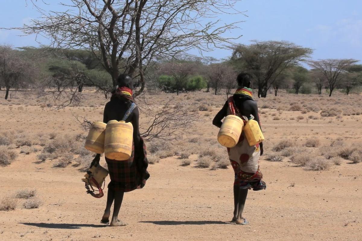 Two people walking in Africa with water cans