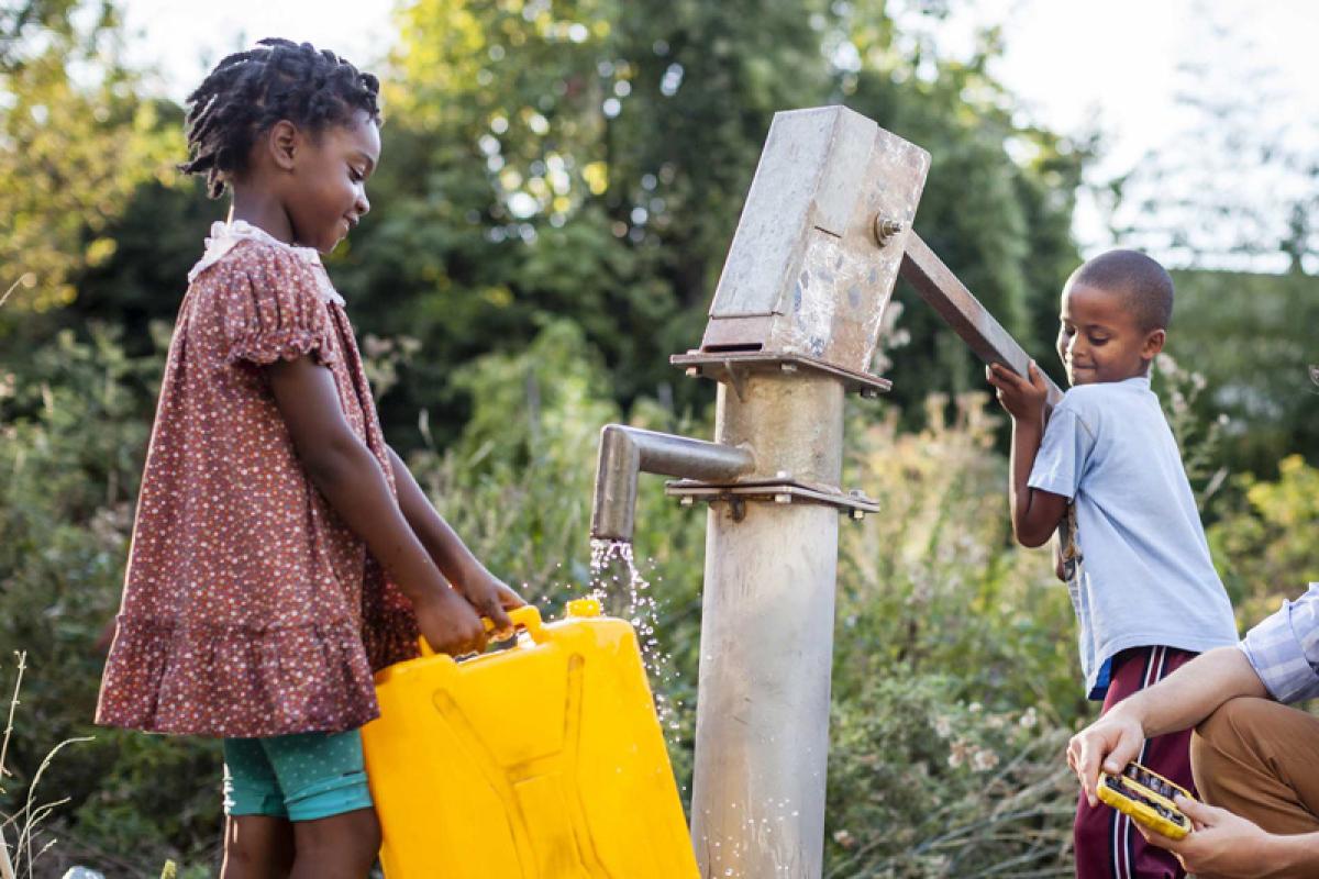 Kids pumping water at a hand pump