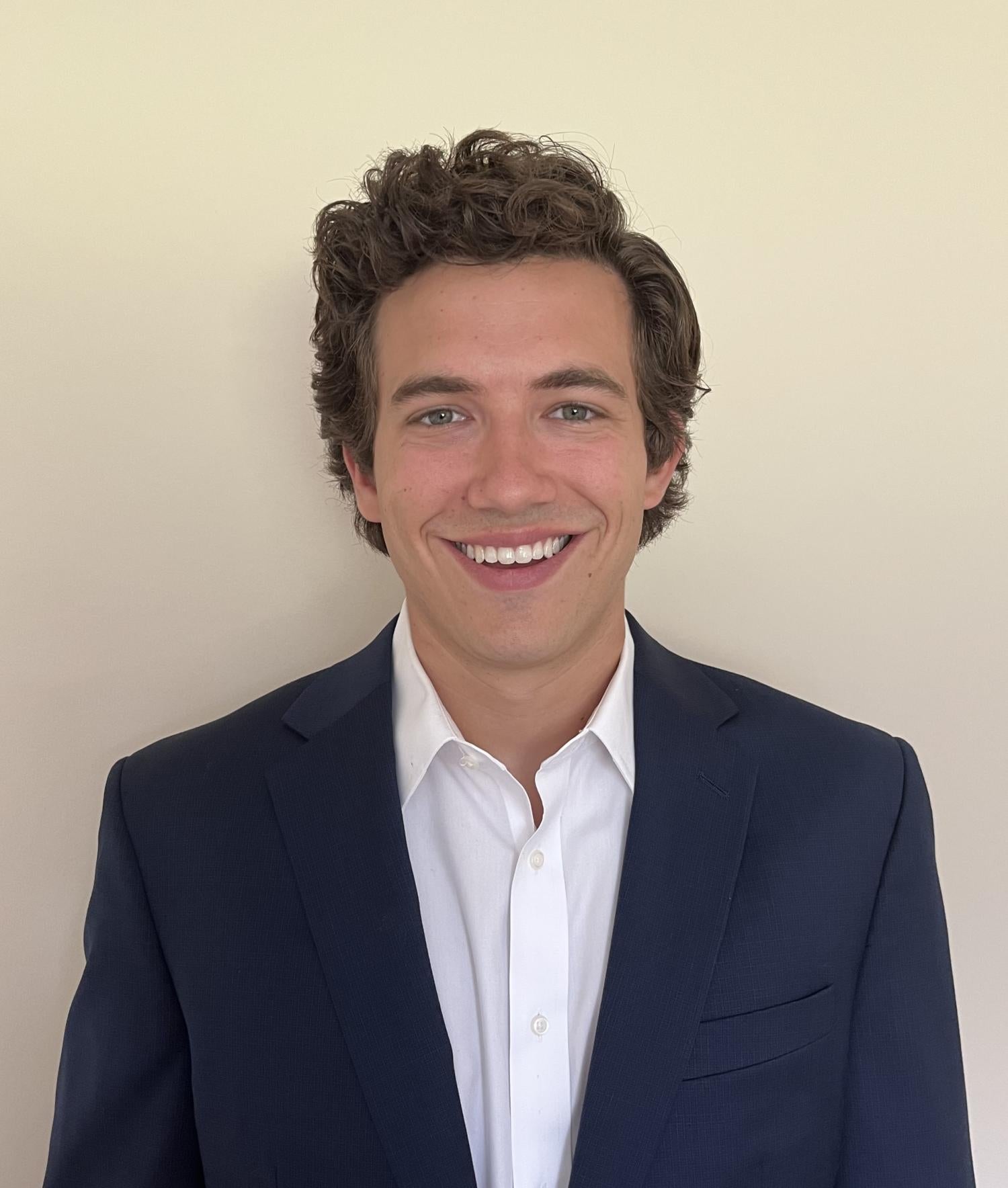 Man in white button up and jacket smiling