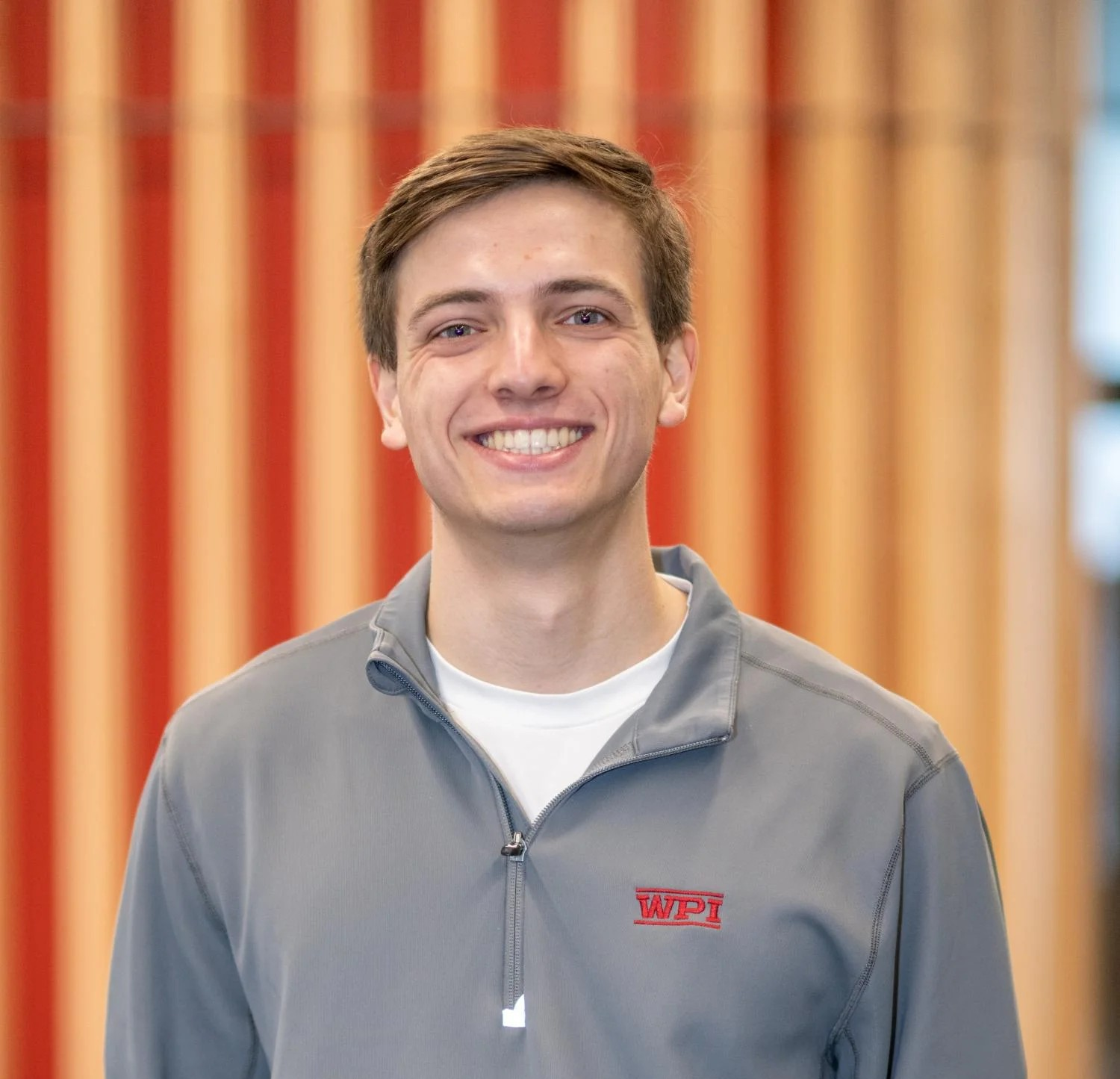 Man smiles wearing a long sleeve gray shirt