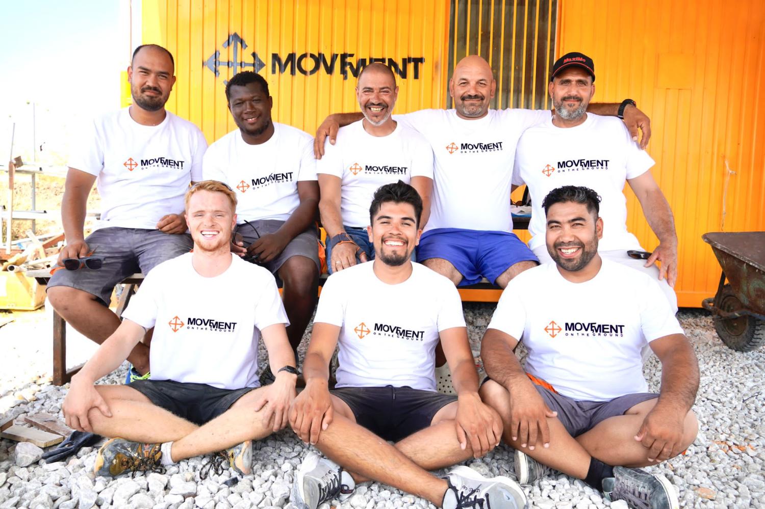 Group of men in shorts and t shirts that are volunteers posing for a photo