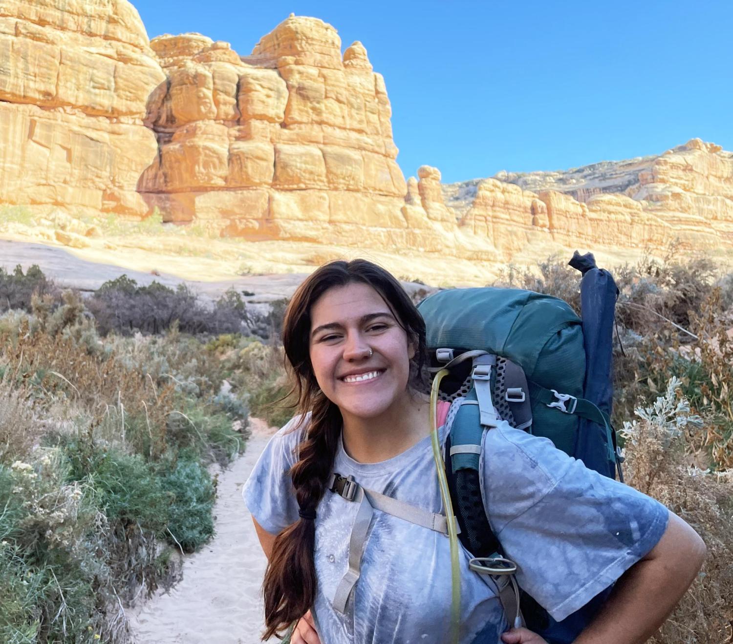 Student standing in front of a rock formation at sunrise