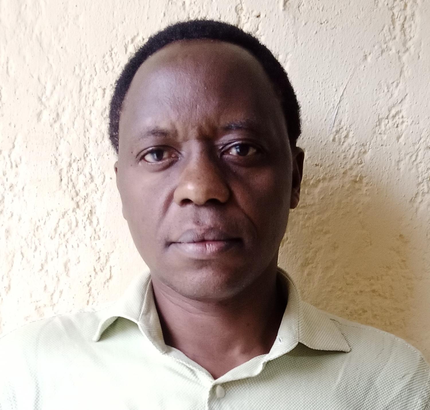 Man with short black hair, green shirt standing outside