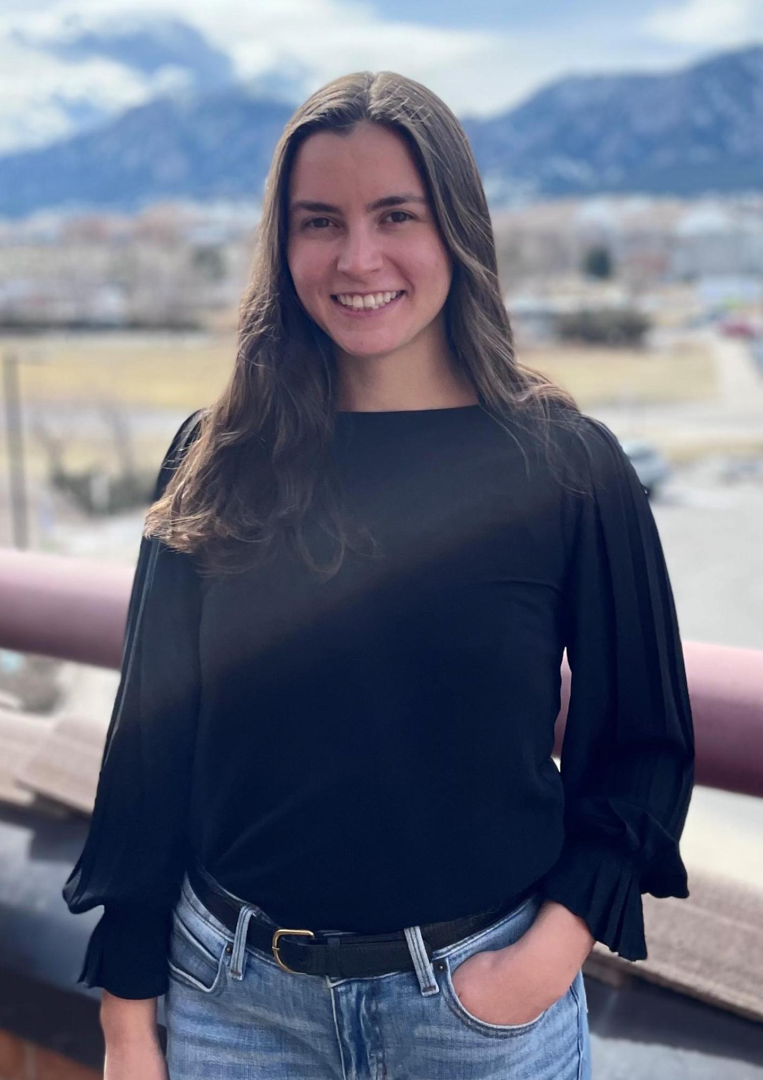 Student standing with a black shirt and the Boulder Flatiron mountains in the background