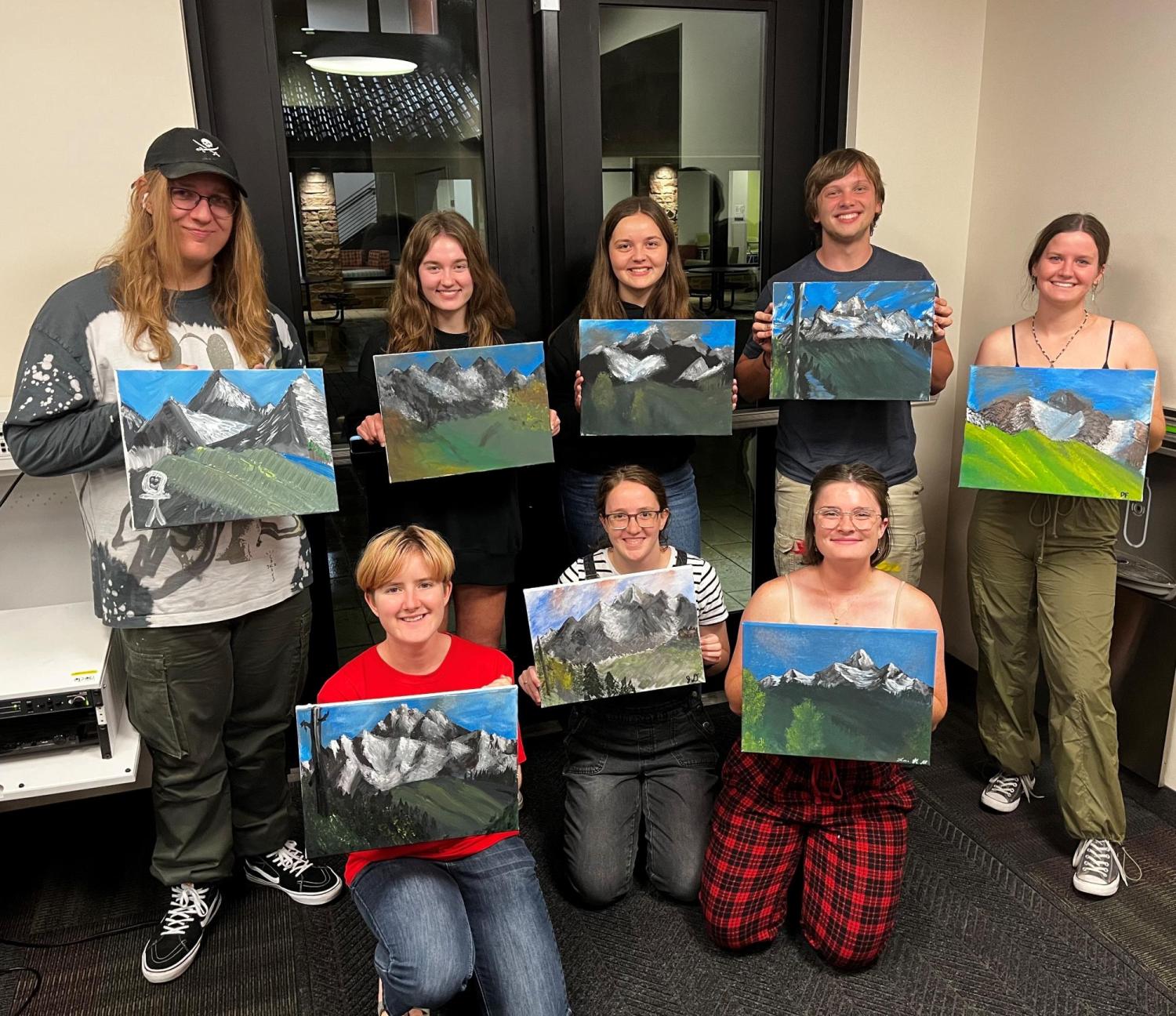 Students holding up paintings they did of the mountains