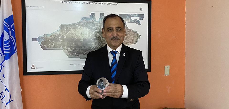 Dr. Sarim Al-Zubaidy holding his award in front of a map of the Bahamas
