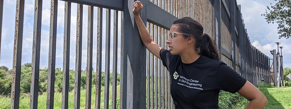 Woman looking over the border wall into Mexico