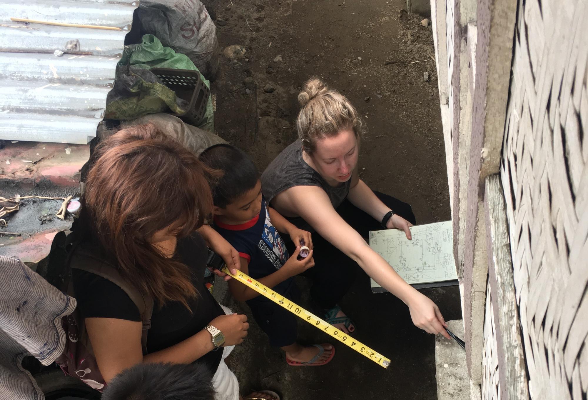 Casie Venable taking housing measurements with local community members.
