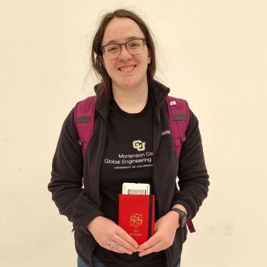 Student holding a passport wearing a backpack ready to travel