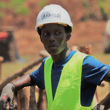 student standing on bridge wearing a hard hat and reflective vest