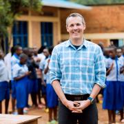 Director standing in front of water purification tank at a school in Rwanda