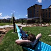 Student lying in hammock outside of a building on campus